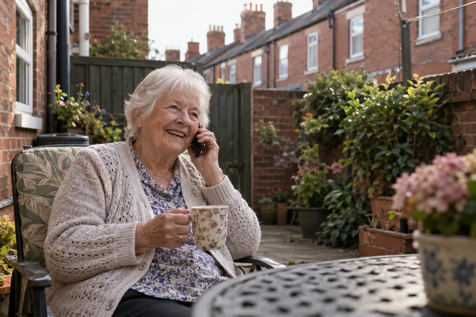 Older woman in Leeds having tea in her garden, talking to her daughter on the phone